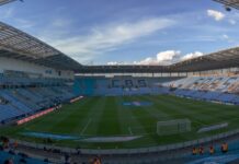 Wide view across the pitch and sky-blue stands at Coventry Building Society Arena